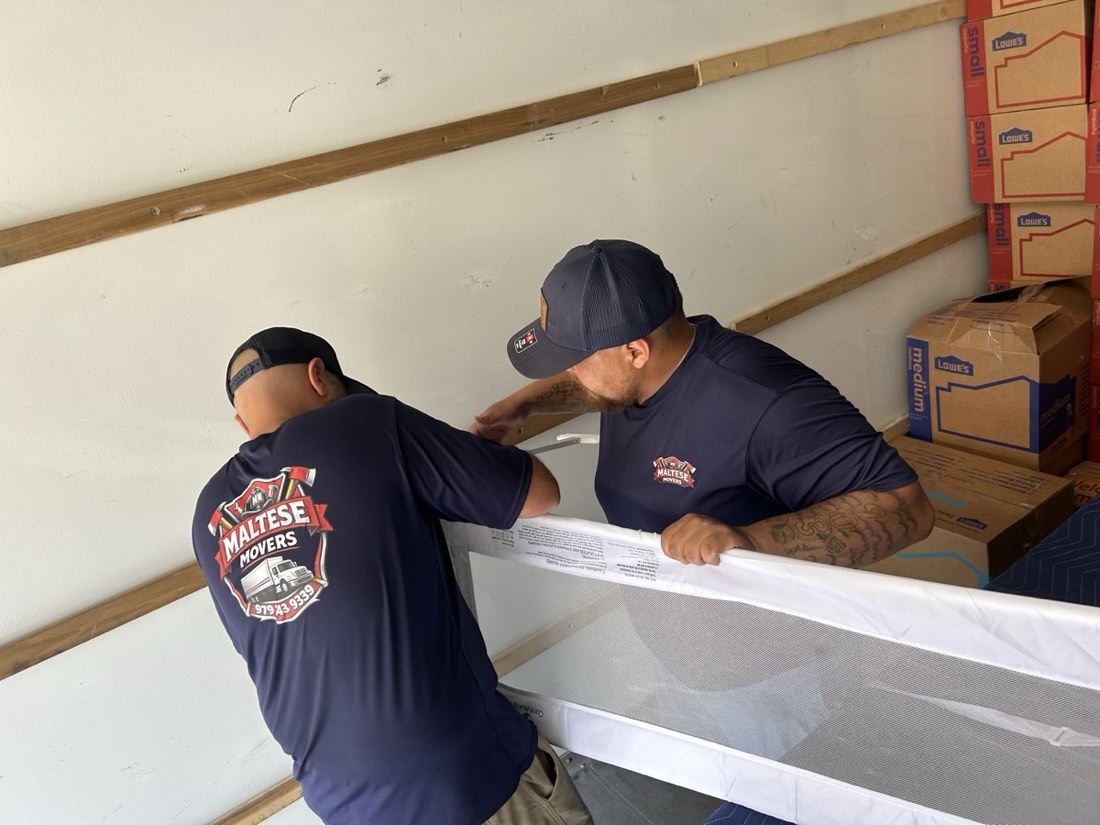 Maltese Movers crew member carrying a mattress into a moving truck